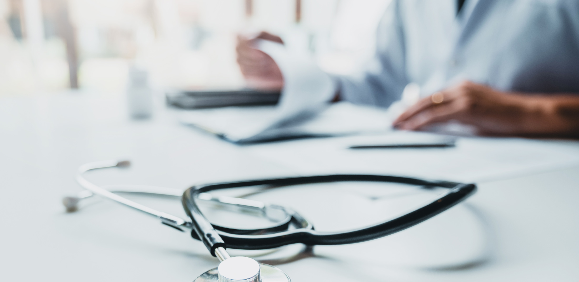 Stethoskop auf Schreibtisch, Arzt bei Anamnese und Dokumentation, medizinische Untersuchung in Anästhesiepraxis