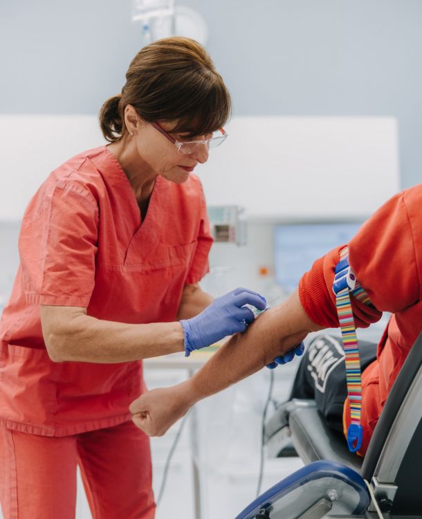 Anästhesie-Mitarbeiterin legt venösen Zugang bei Patient, Vorbereitung für Narkose in moderner Praxis